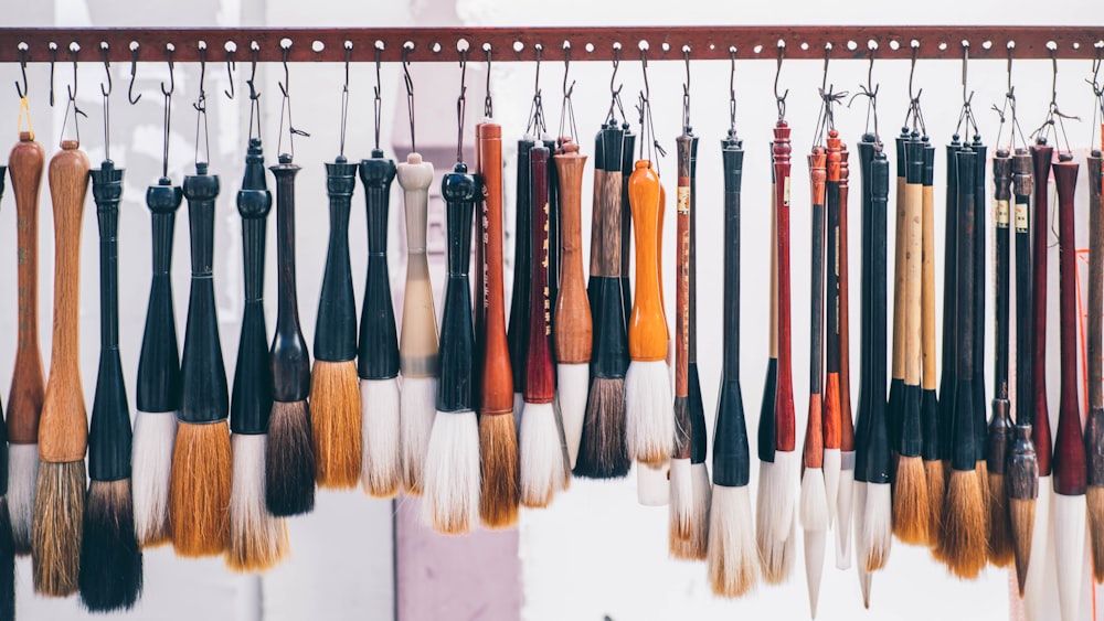 a bunch of different colored brushes hanging from hooks