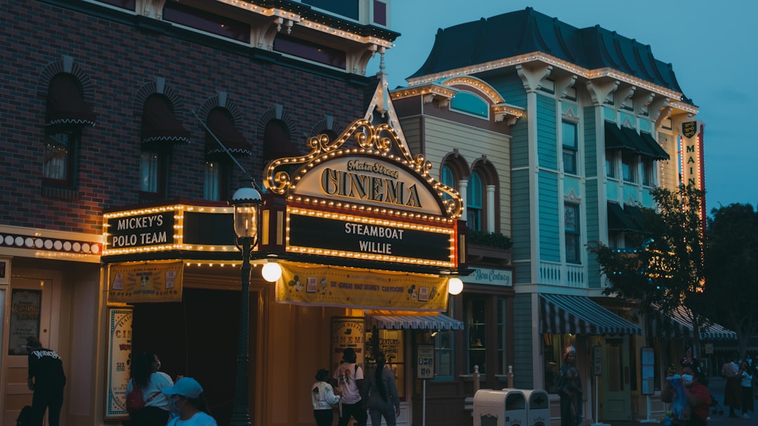 a theater marquee on a city street at dusk, The Disneyland Main Street Cinema plays "Steam Boat Willie"