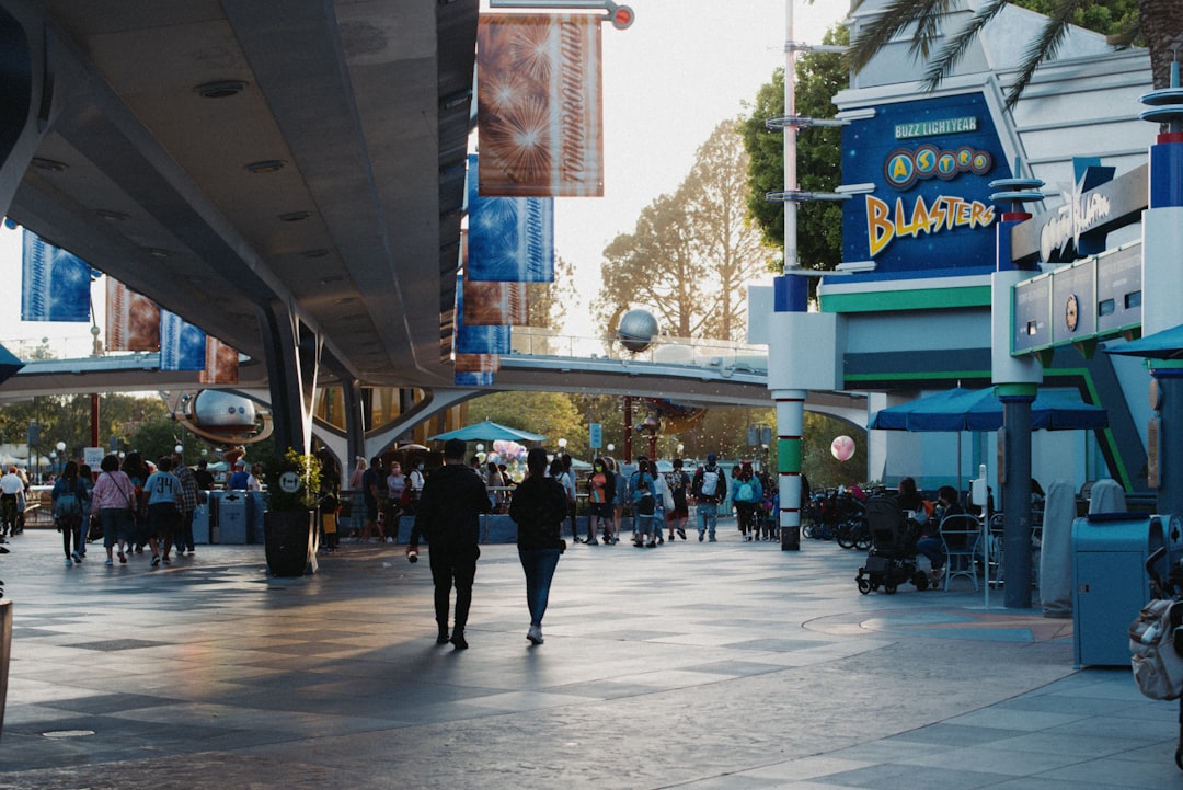a group of people walking down a street under a bridge, Buzz Lightyear Astro Blasters at Disneyland, CA