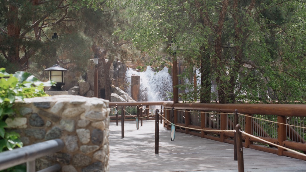 a wooden walkway with a waterfall in the background