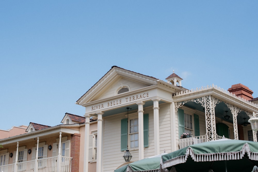 a white house with green awnings and a clock tower