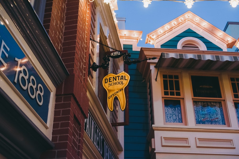 a yellow dental sign hanging from the side of a building
