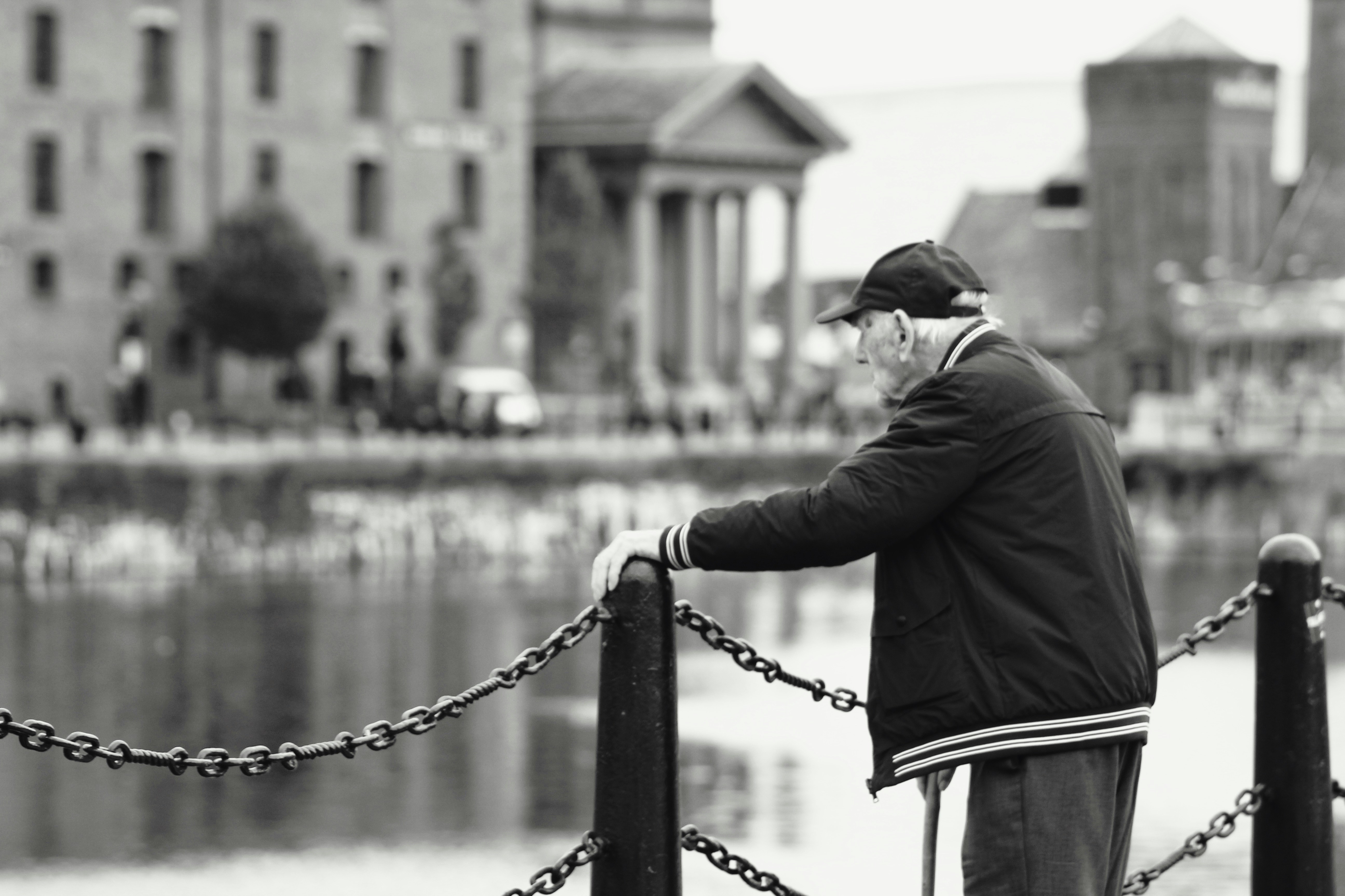 a man standing next to a chain fence near a body of water