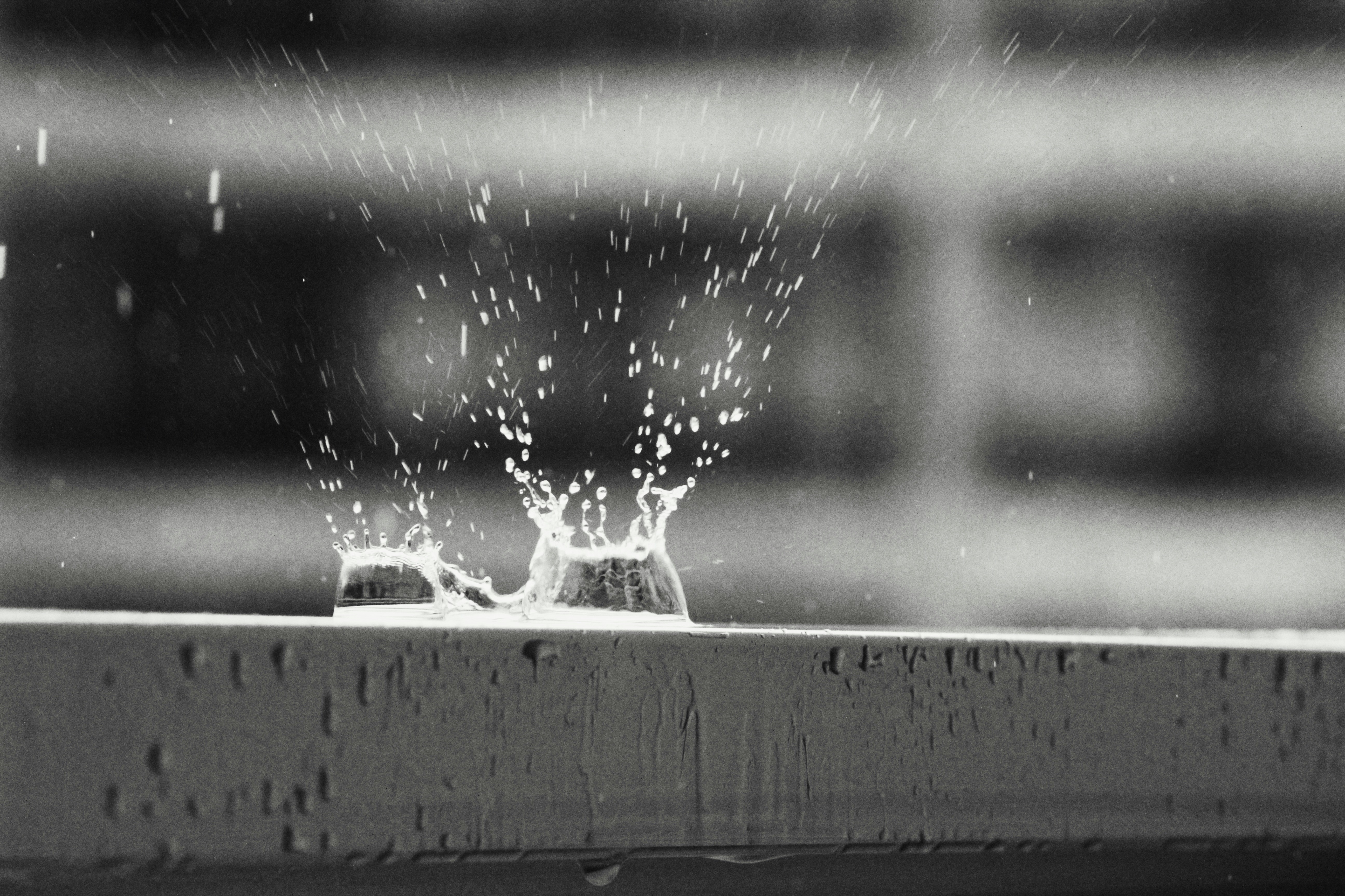 a black and white photo of water splashing out of a window