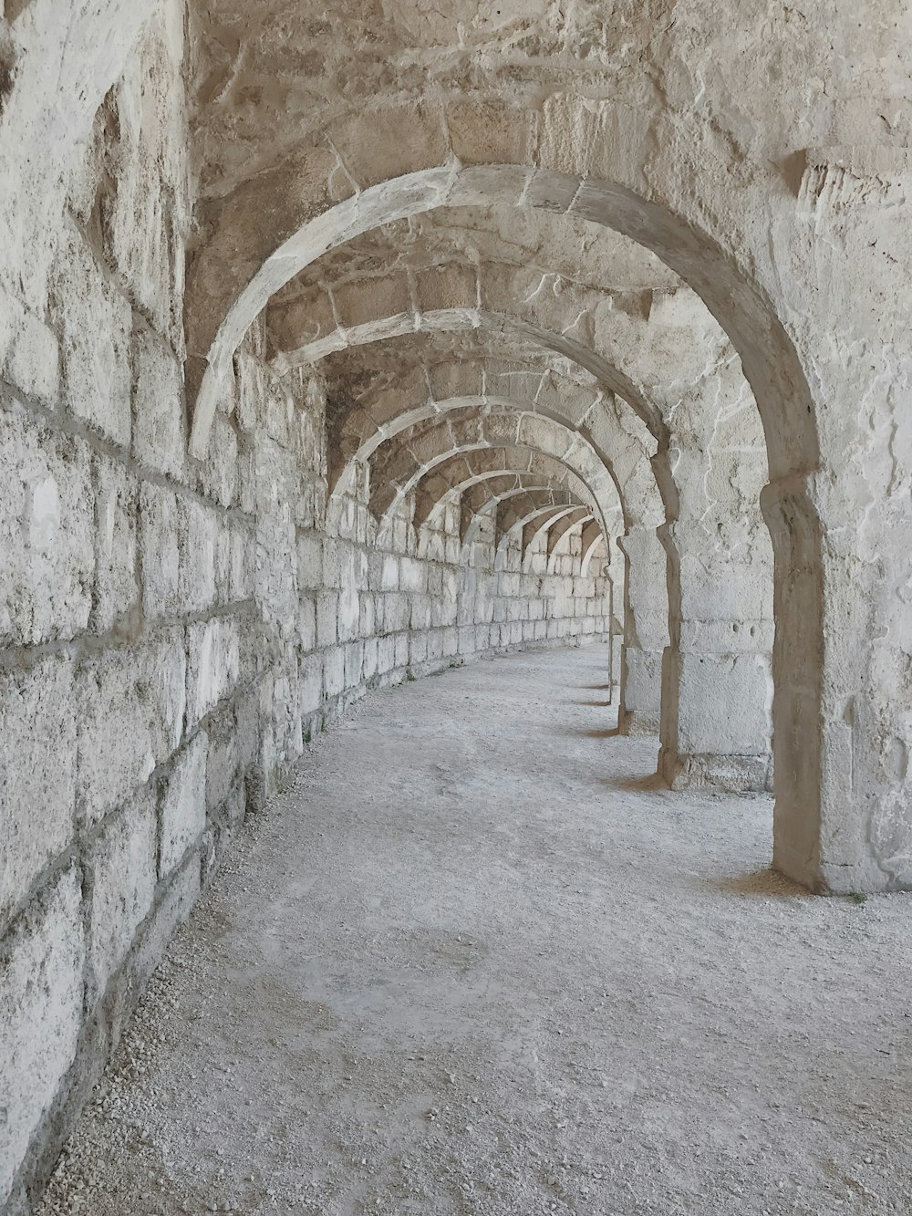 a long stone tunnel with arches and cobblestones