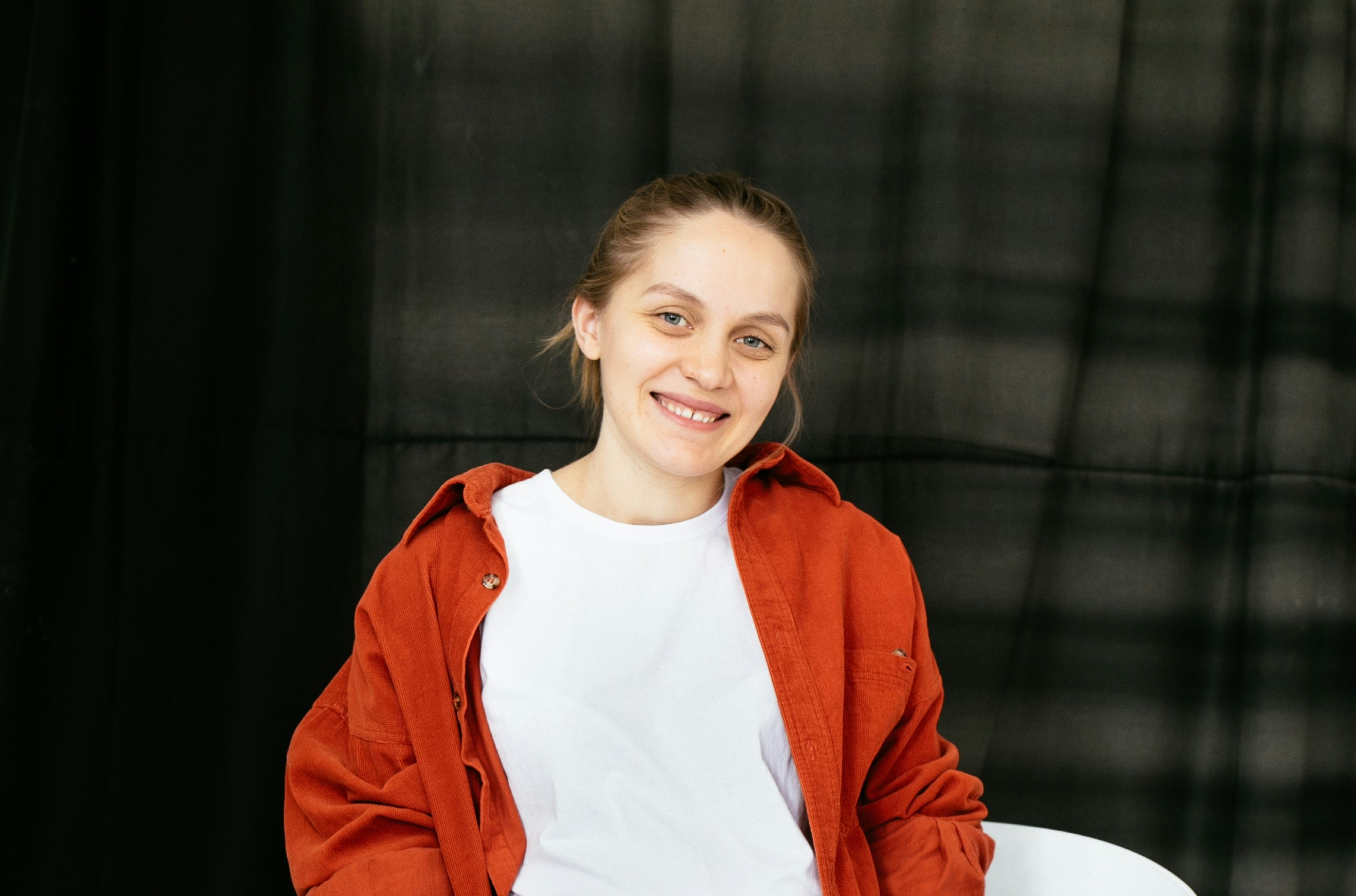 A woman in a red jacket sitting on a white chair