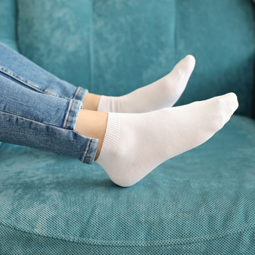 a woman sitting on a blue couch wearing white socks