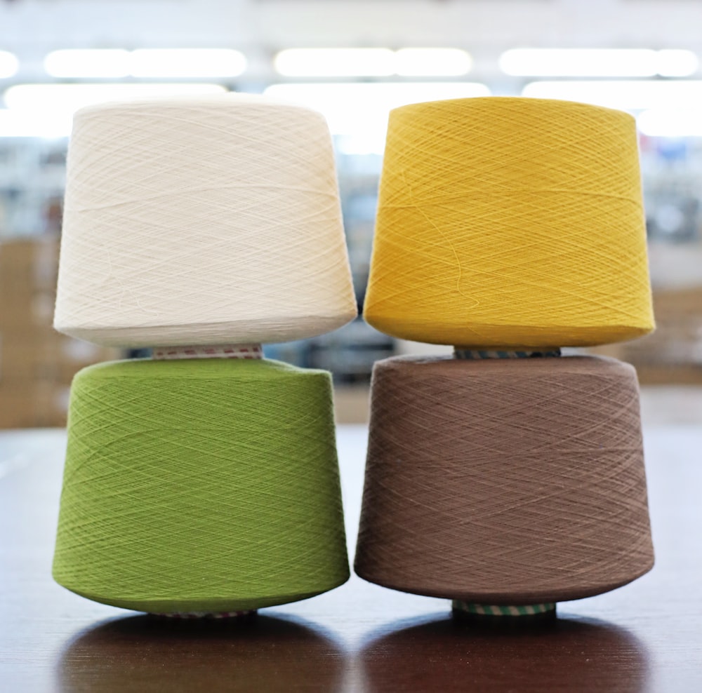 three different colored yarns sitting on top of a table