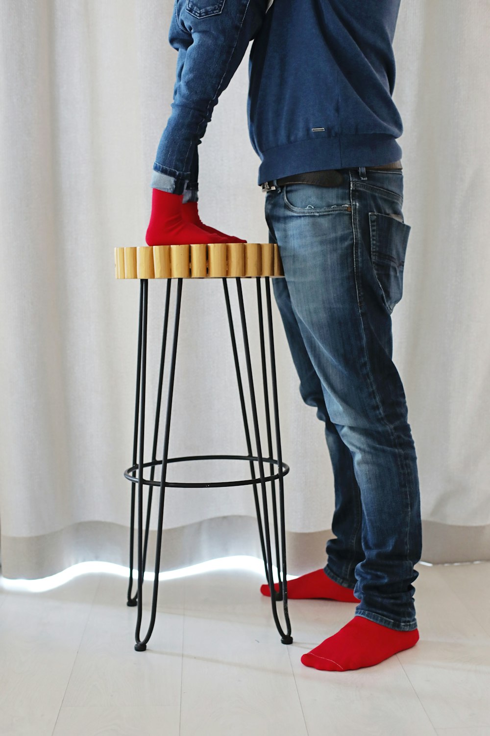 a man standing on a stool with a pair of red shoes on top of it