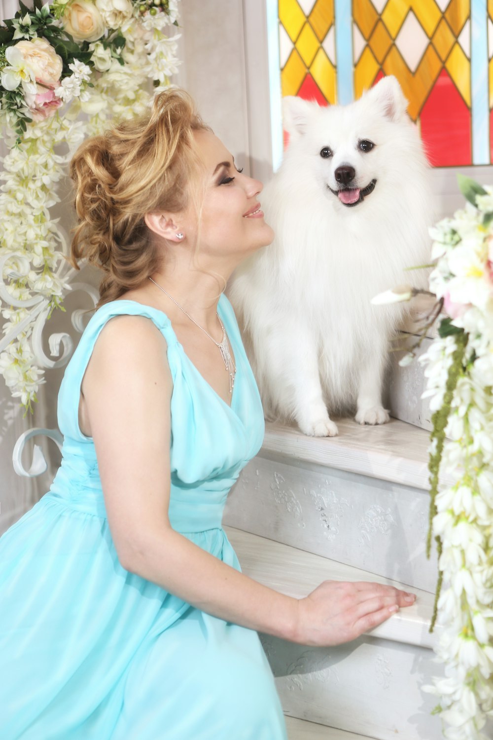 a woman in a blue dress sitting next to a white dog