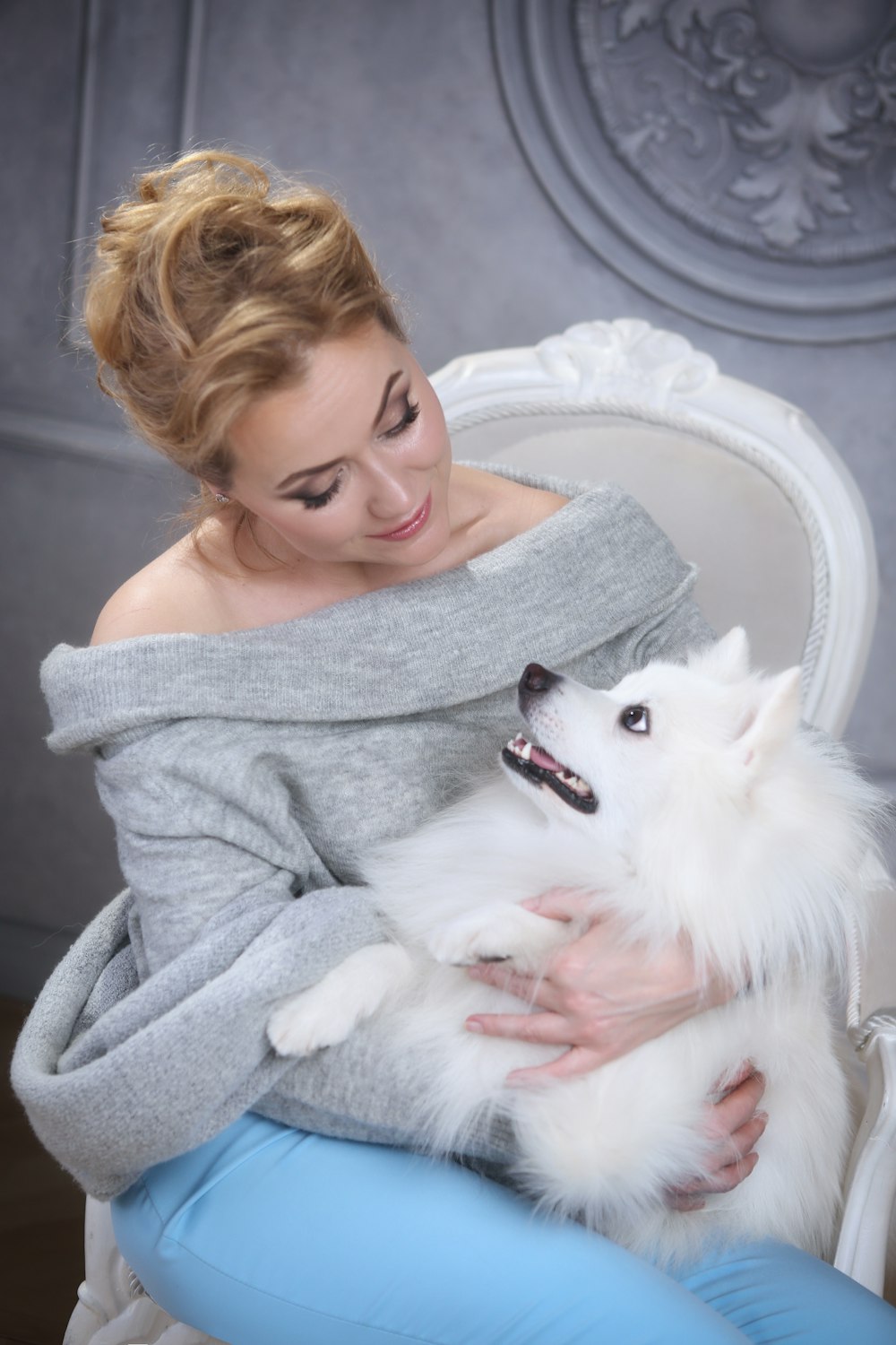 a woman sitting on a chair holding a white dog