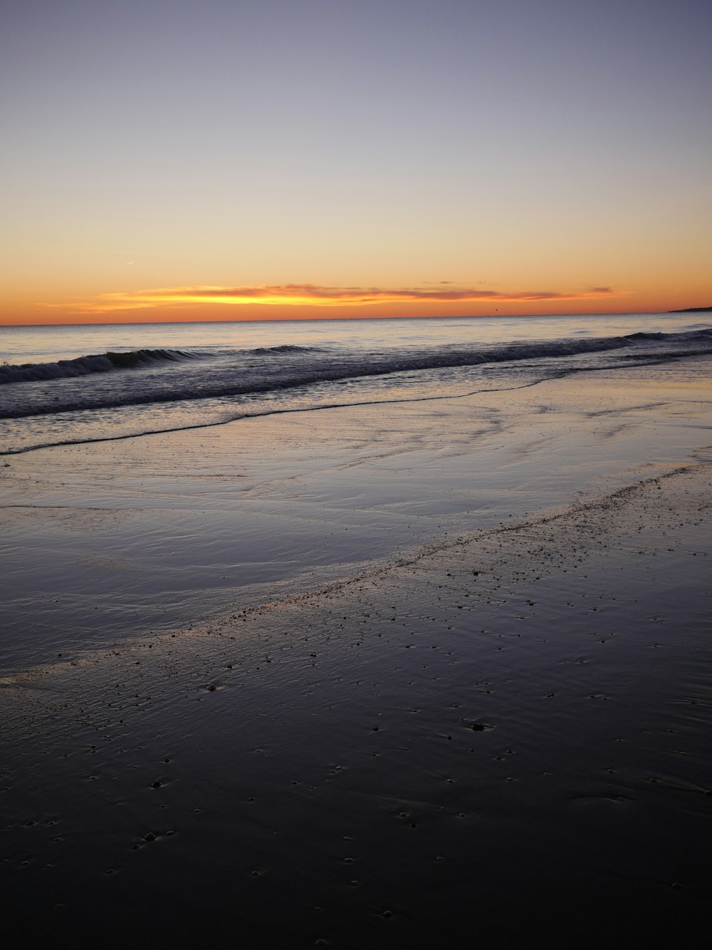 the sun is setting over the water at the beach