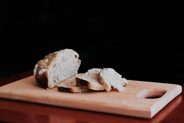 Close-up of freshly baked crusty bread on a wooden board with a black and white background