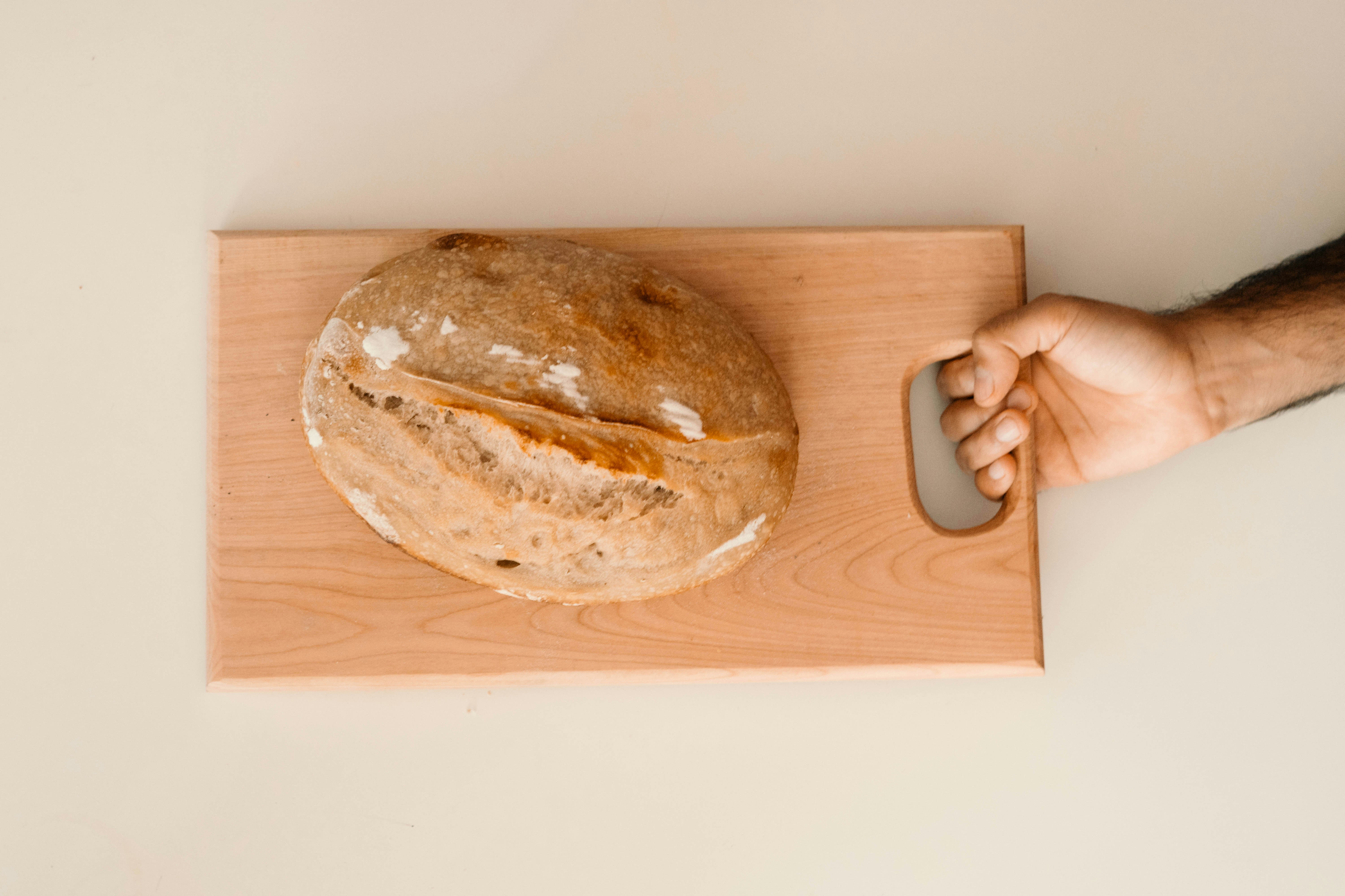 a loaf of bread sitting on top of a wooden cutting board, 