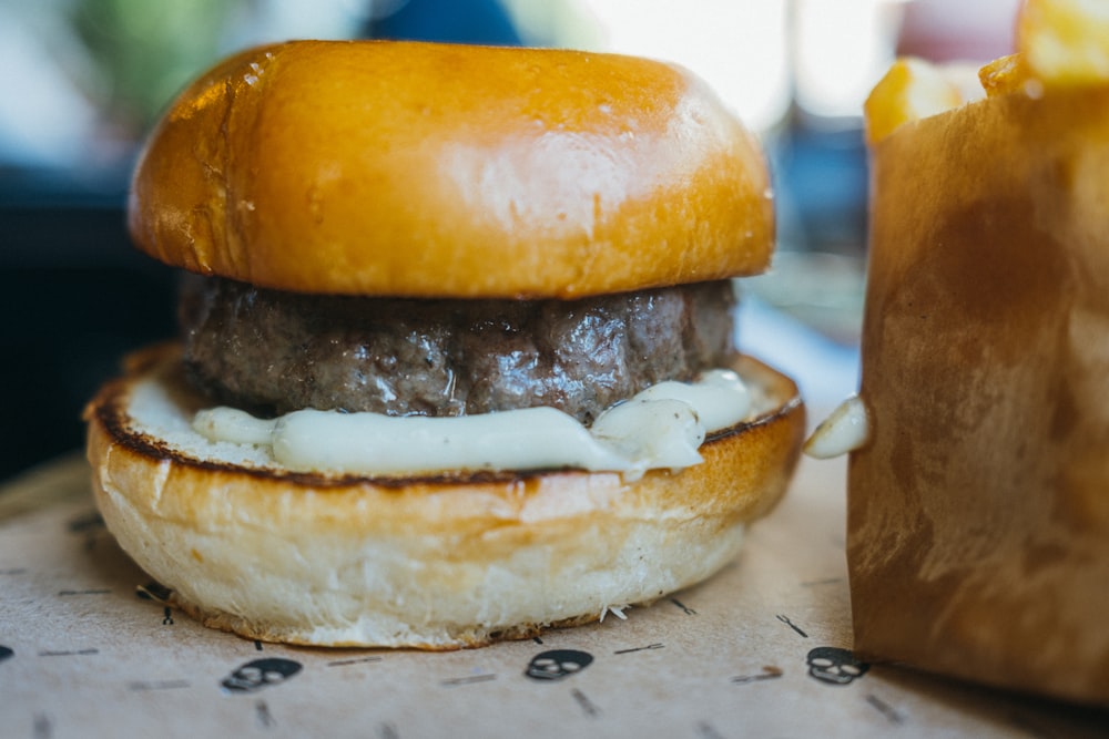 a hamburger sitting on top of a table next to a bag