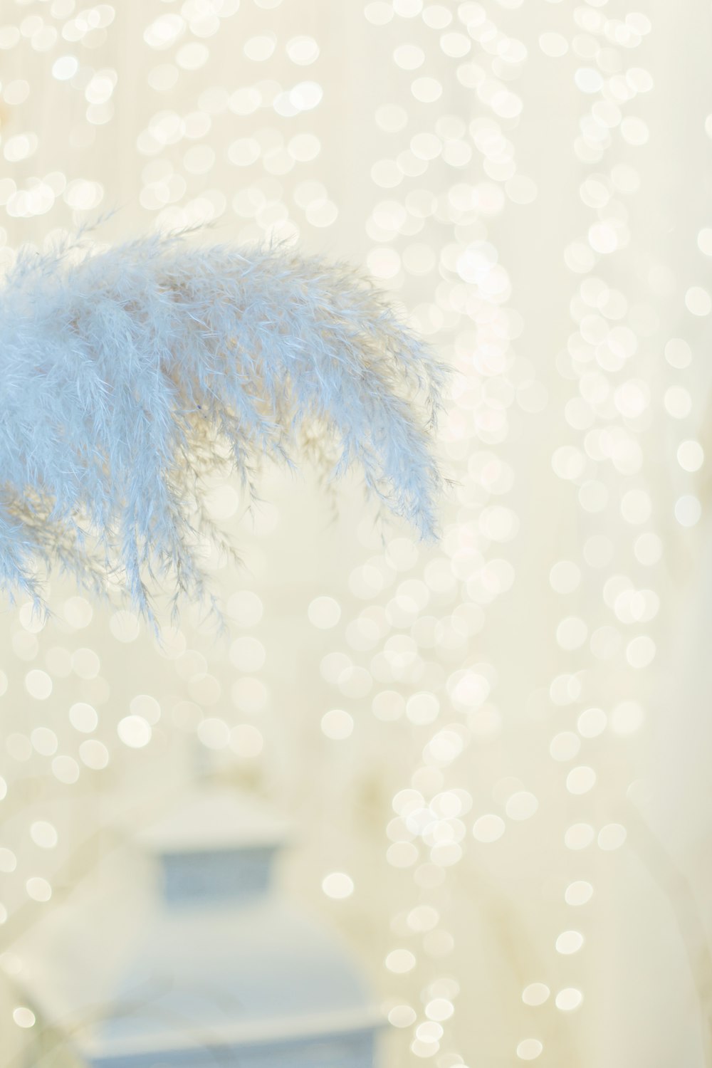 a blue vase with some white feathers on it