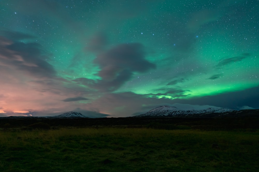 a green and purple sky filled with stars and clouds