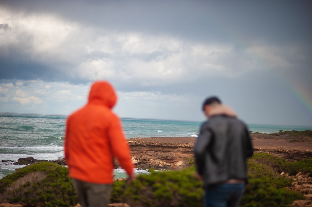 a couple of men standing on top of a lush green hillside