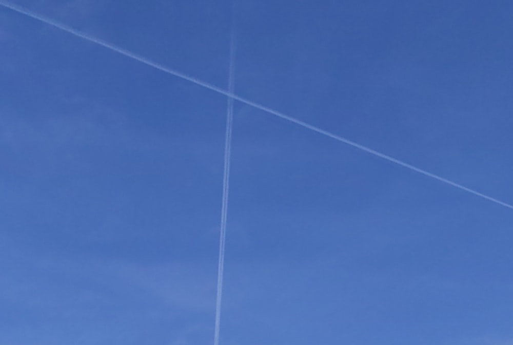 a plane flying through a blue sky with contrails in the sky