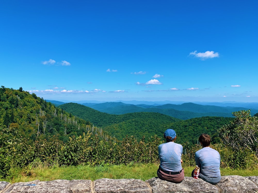 a couple of people sitting on top of a stone wall