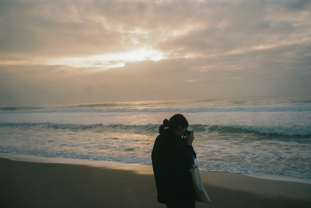 a woman standing on a beach next to the ocean