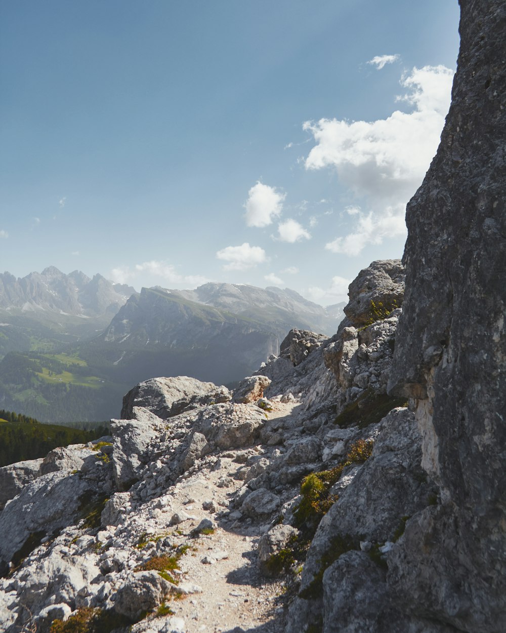 a rocky mountain trail with a view of mountains in the distance