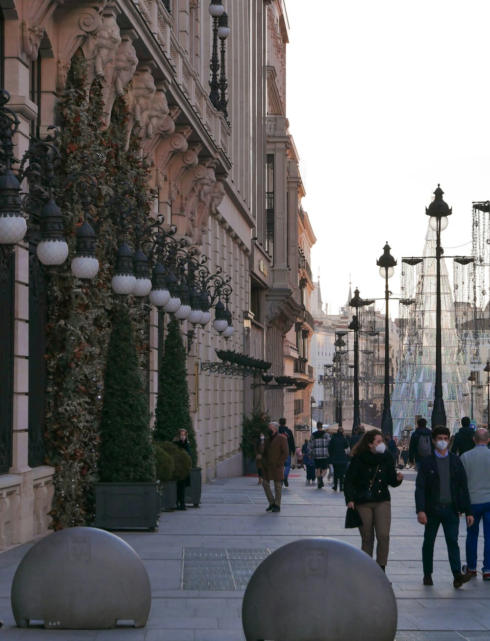 a group of people walking down a street next to tall buildings