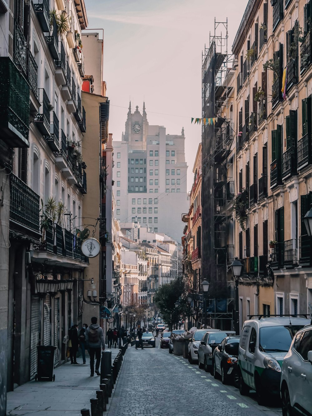 a city street lined with parked cars and tall buildings