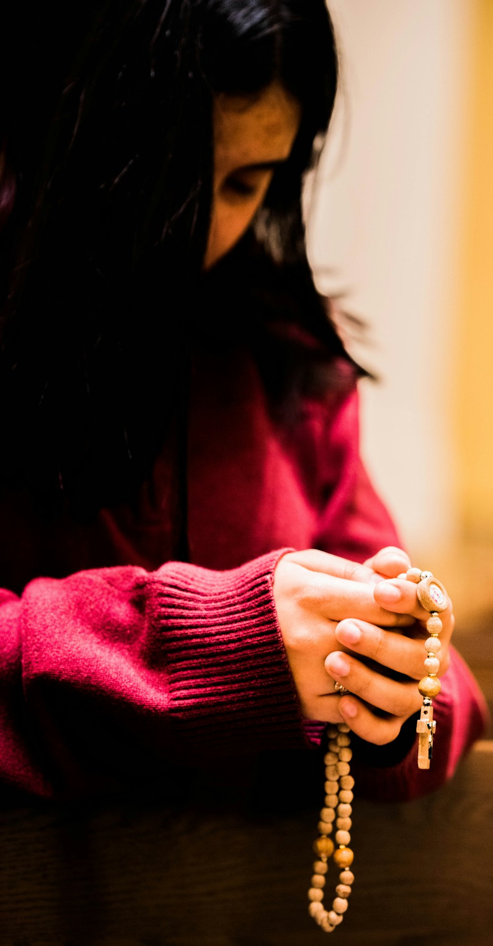 a woman in a red sweater holding a rosary