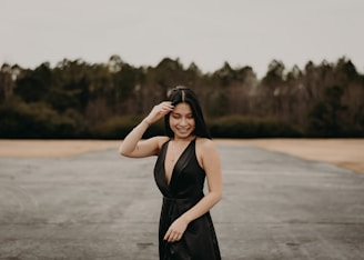 a woman in a black dress standing in a parking lot