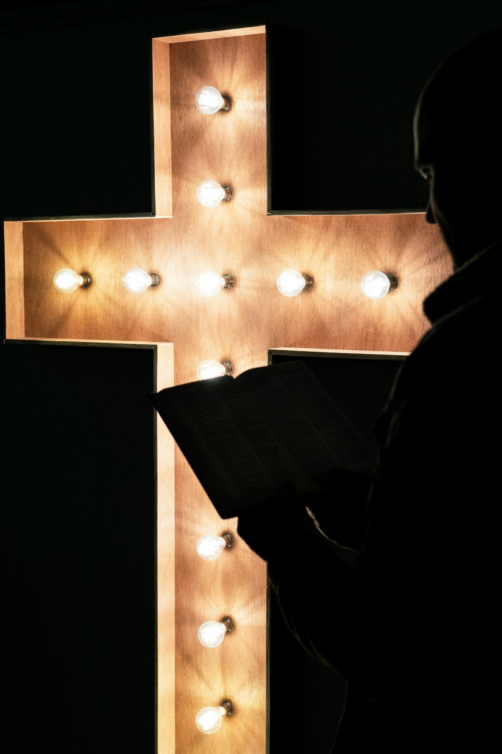a person reading a book in front of a cross