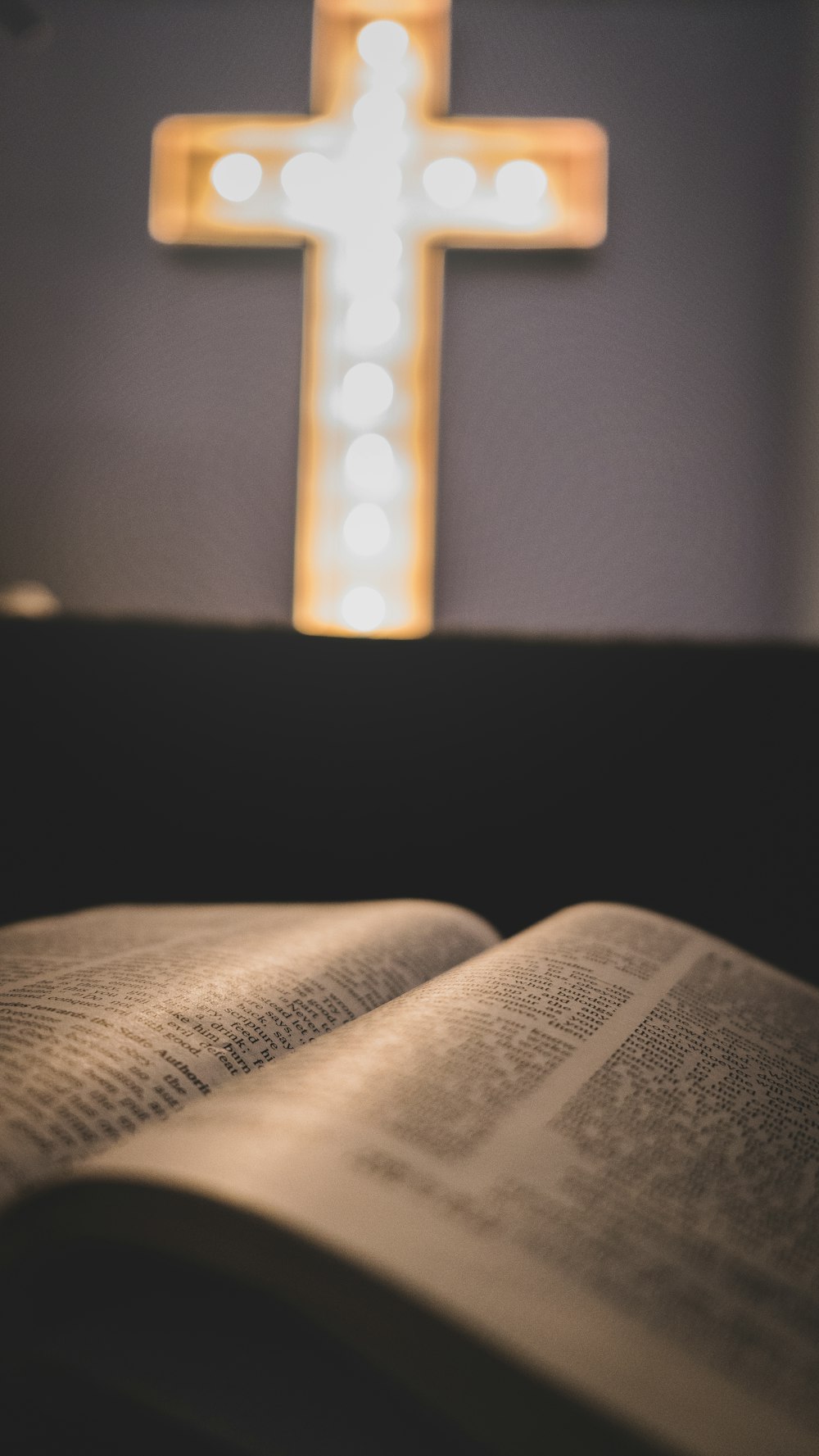 an open book with a lighted cross in the background