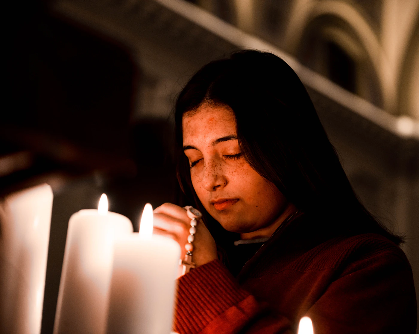 A church member kneeling in quiet prayer before a candle-lit shrine