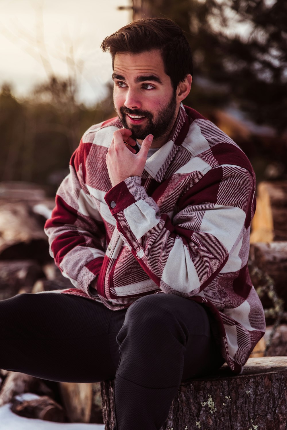 a man sitting on a tree stump with his finger in his mouth