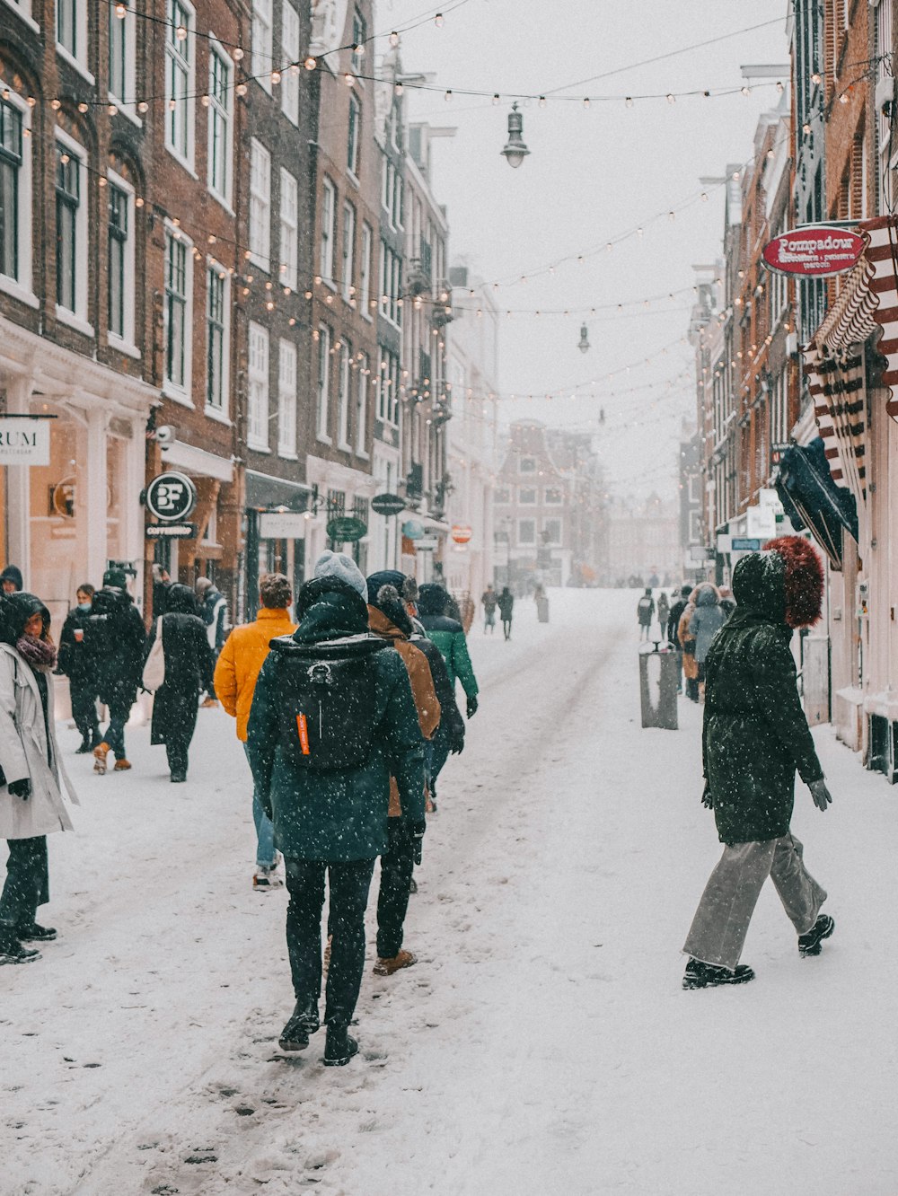 a group of people walking down a snow covered street