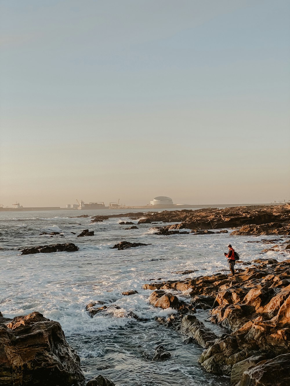 a man standing on a rocky shore next to the ocean