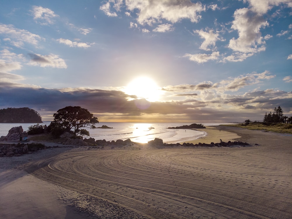 the sun is setting over a sandy beach