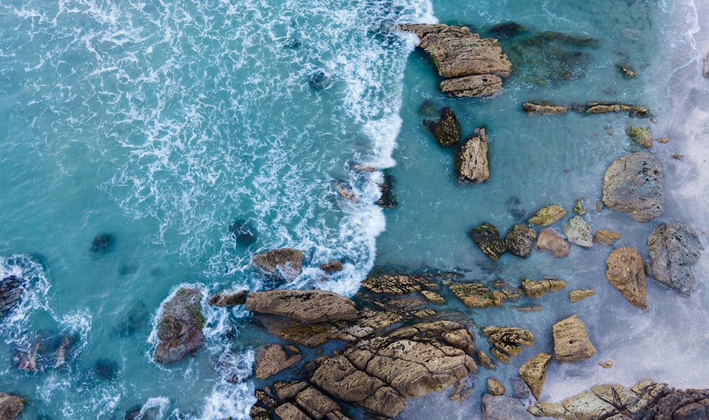 an aerial view of the ocean and rocks