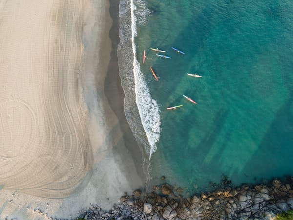 Kayakers setting off from calm sandy shore