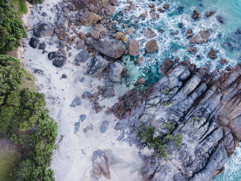 uma vista aérea de uma praia com rochas e água