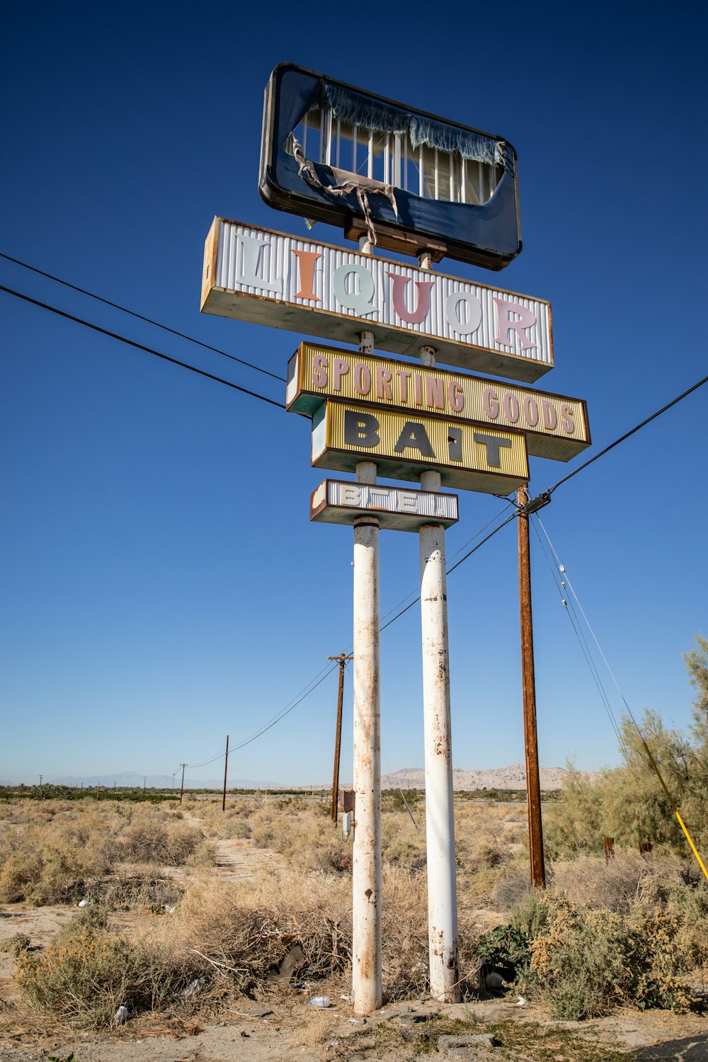 a sign in the middle of a desert with power lines in the background