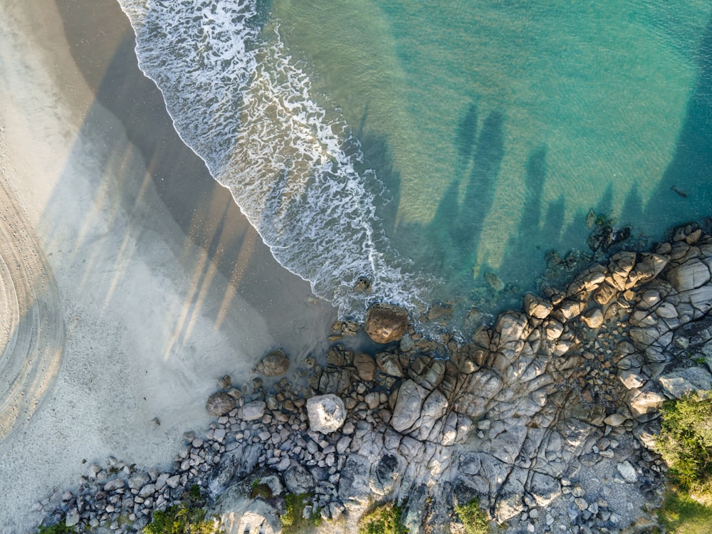 an aerial view of a beach with rocks and water