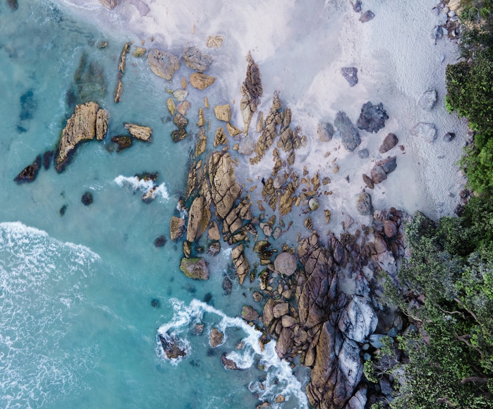 an aerial view of a beach with rocks and water