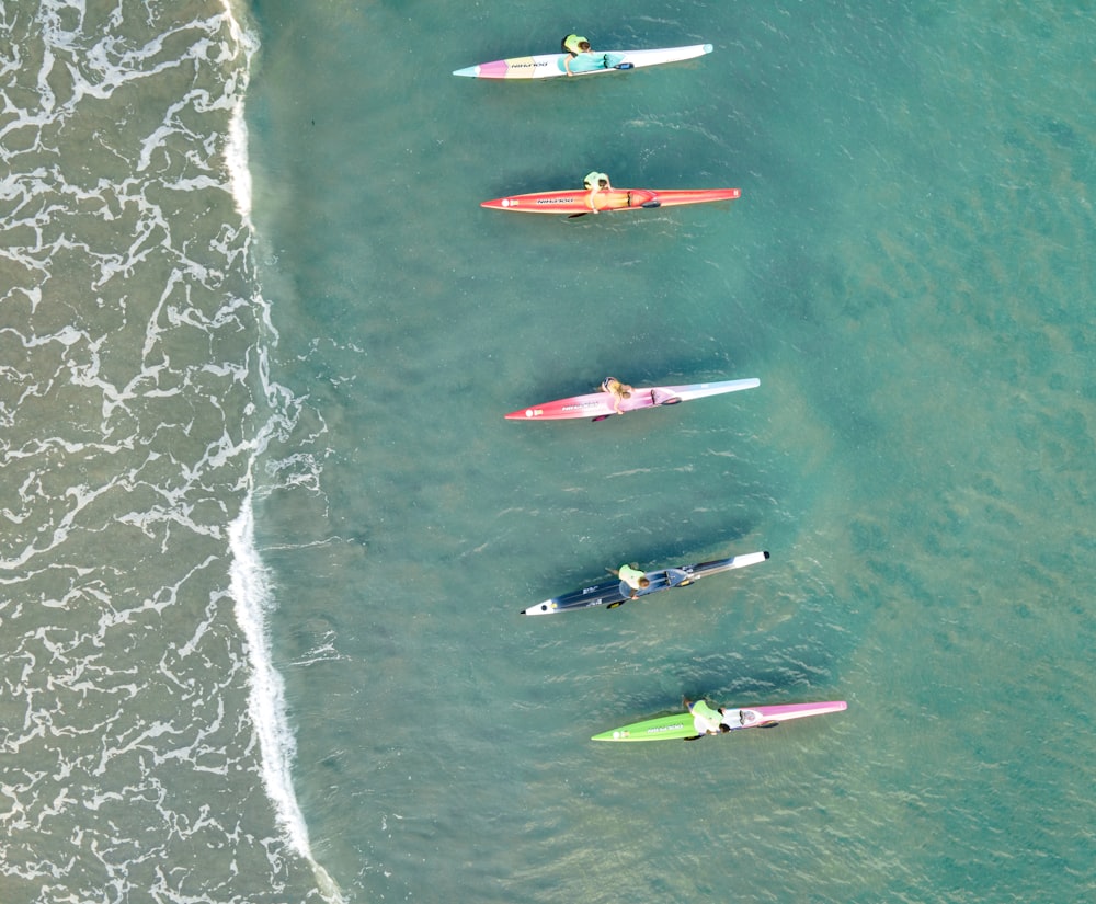 a group of people riding on top of surfboards in the ocean