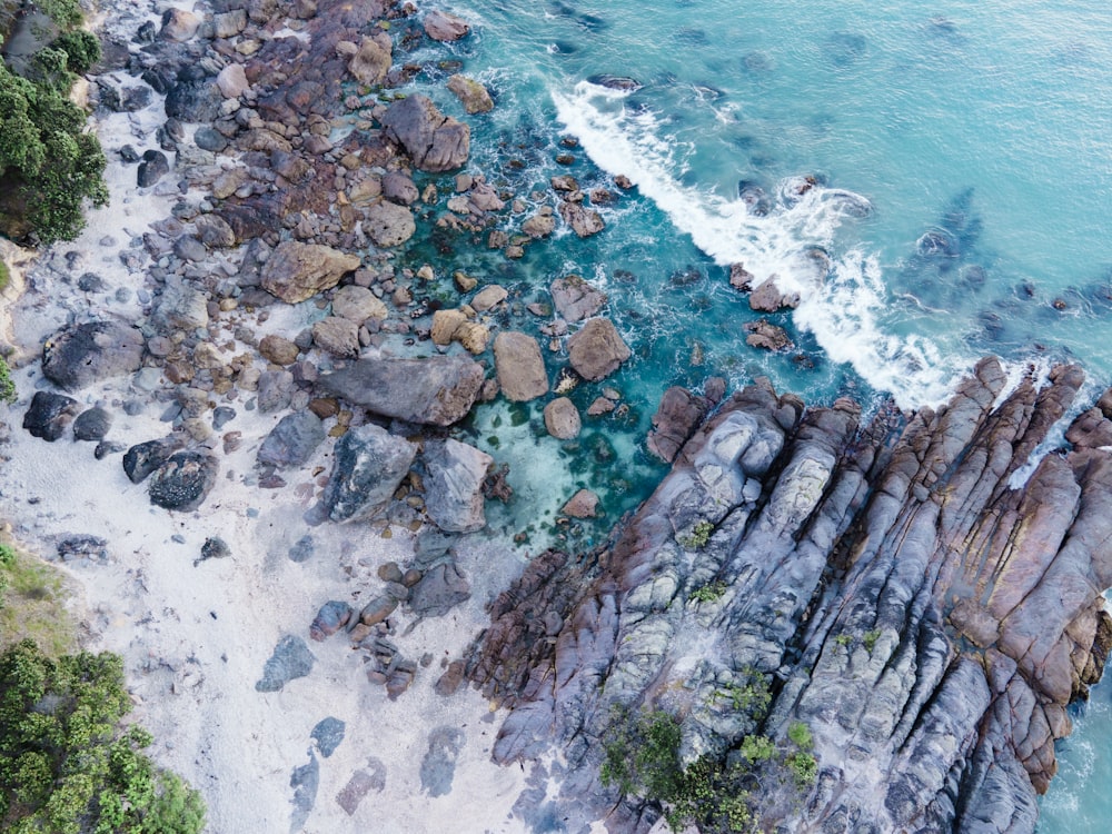 an aerial view of a beach with rocks and water