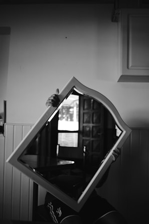 Close-up of an antique mirror reflecting a dimly lit, empty Victorian parlor.