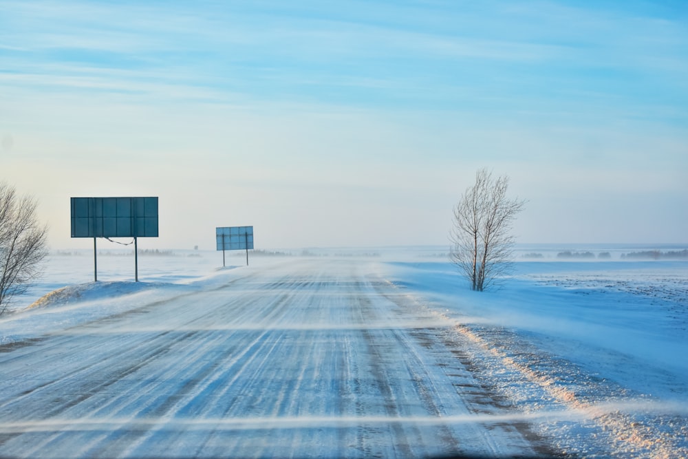 a snow covered road with two signs in the distance