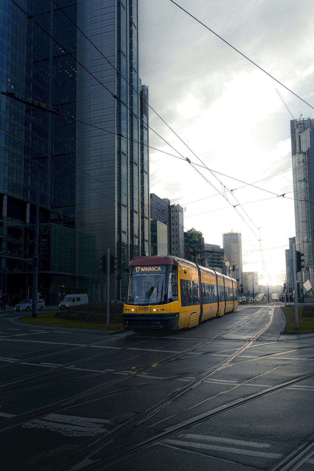 a yellow train traveling down a street next to tall buildings