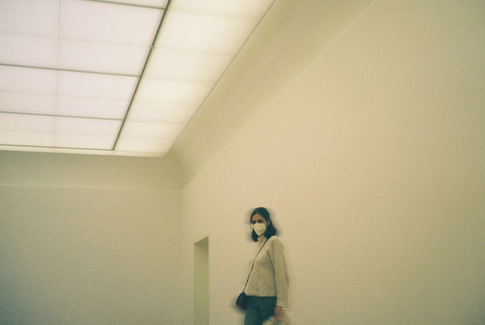 a woman walking down a hallway with a handbag