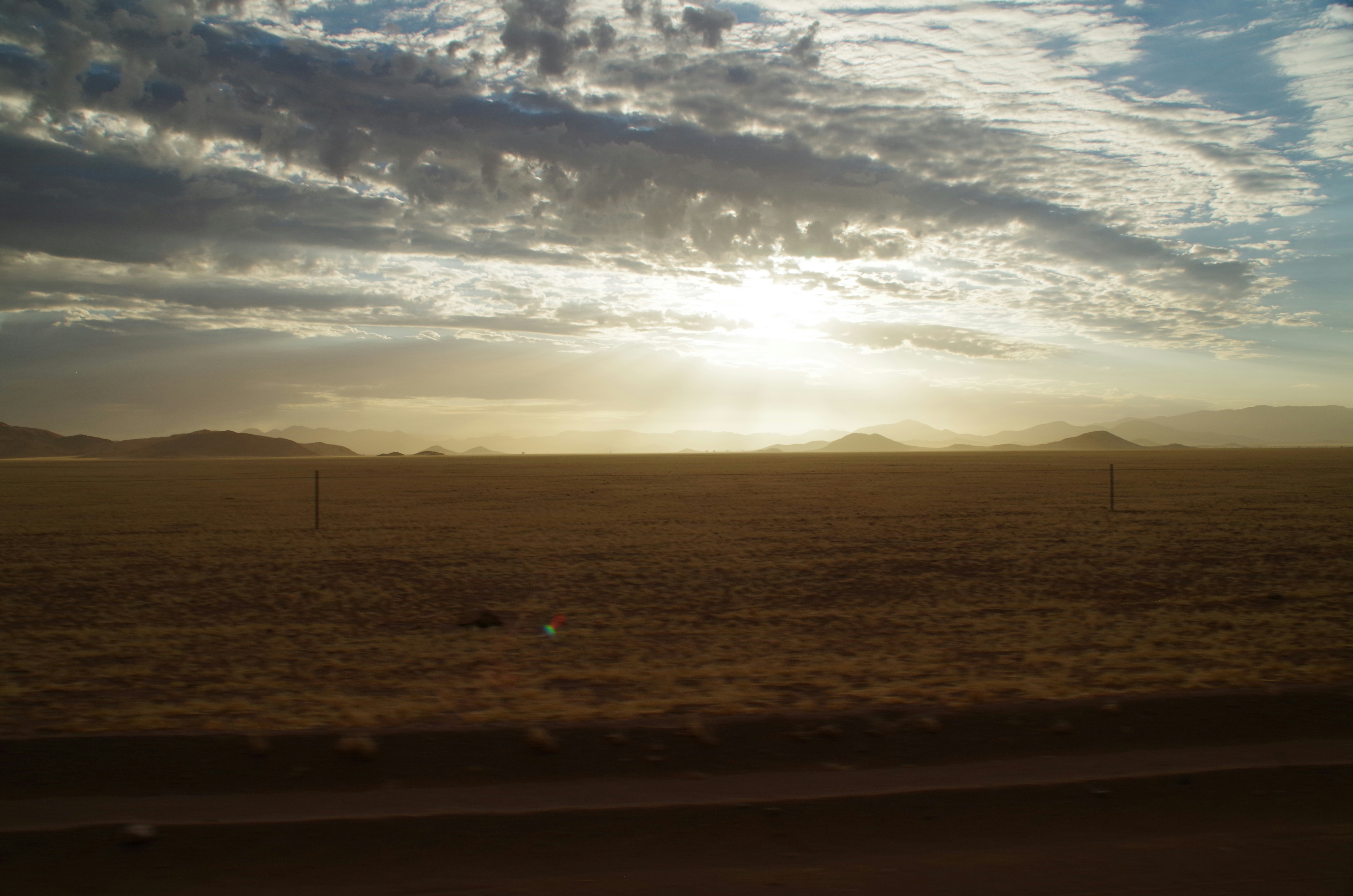 Vast African savanna at golden hour, wide open plains, deep amber sky, atmospheric wilderness depth